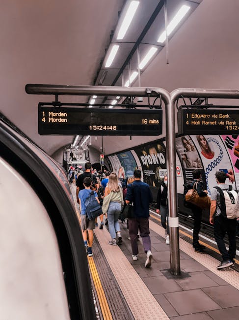 This image depicts a busy London Underground station platform near Edgware Tube Station, with numerous commuters walking along the tiled floor and waiting for the train. The train doors are open, reve